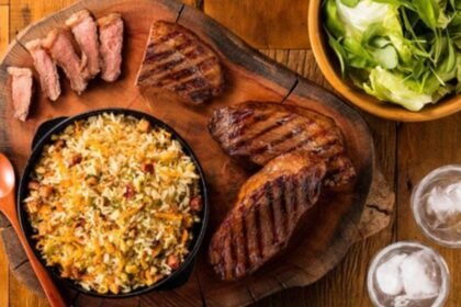 Imagem de um prato com farofa e arroz com carnes de churrasco em volta