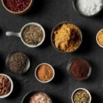 Foto mostra vários temperos em pó coloridos em cima de uma mesa.