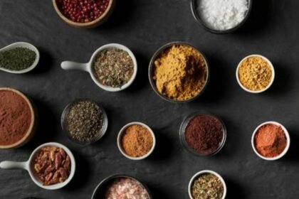 Foto mostra vários temperos em pó coloridos em cima de uma mesa.