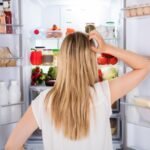Mulher de costas olhando a geladeira
