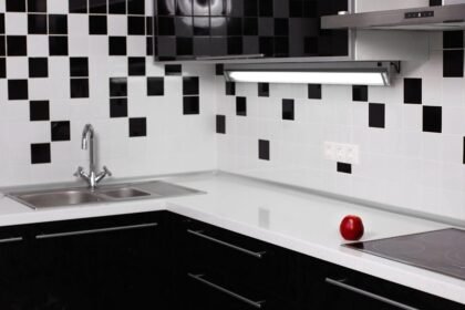 Foto mostra um azulejo de cozinha com pia e bancada.