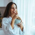 Imagem de uma mulher tomando café na cozinha
