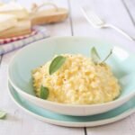 Risoto de queijo dentro de um prato em cima da mesa.