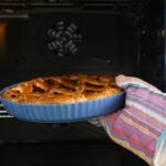 Imagem de uma pessoa colocando uma torta doce dentro do forno