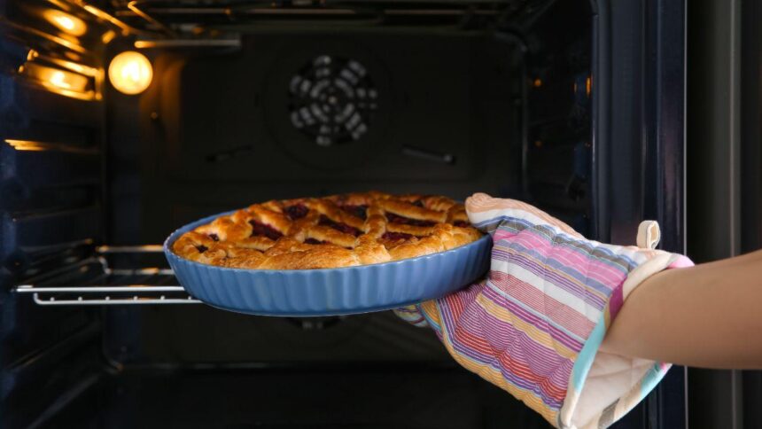 Imagem de uma pessoa colocando uma torta doce dentro do forno