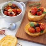 Foto mostra tomate-cereja confitado em cima de um pão de torrada.