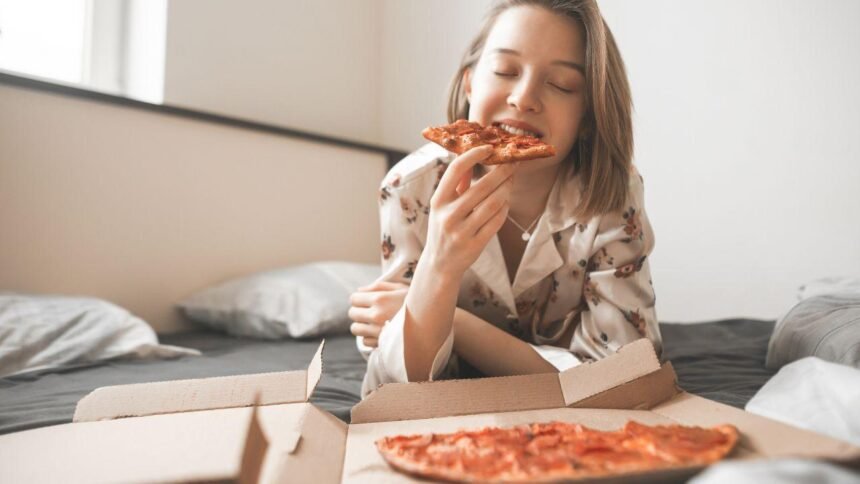 Imagem de uma mulher comendo pizza direto da caixa
