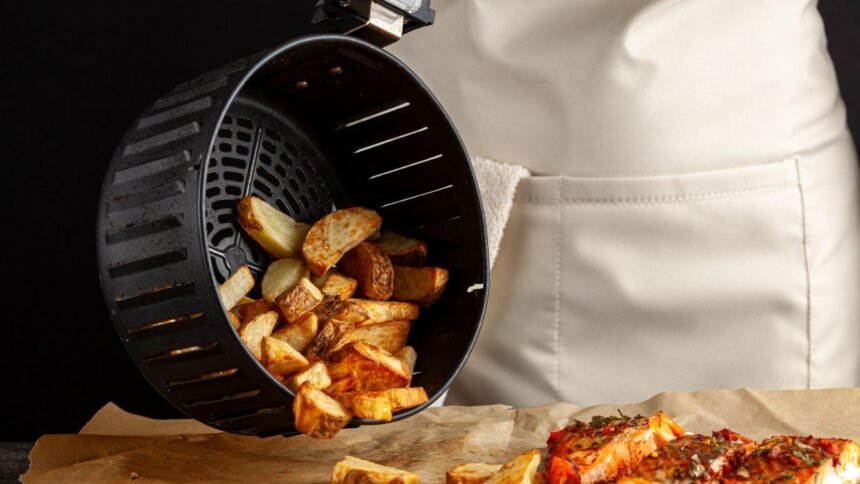 Imagem de uma pessoa tirando batatas do cesto de uma air fryer