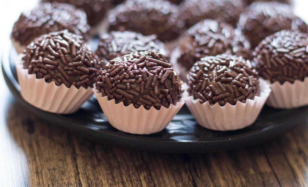 Foto mostra vários brigadeiros enrolados em cima de um prato.